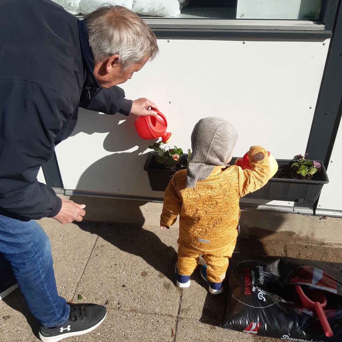 Barn og voksen planter blomster i Tjærbyvejens Vuggestue