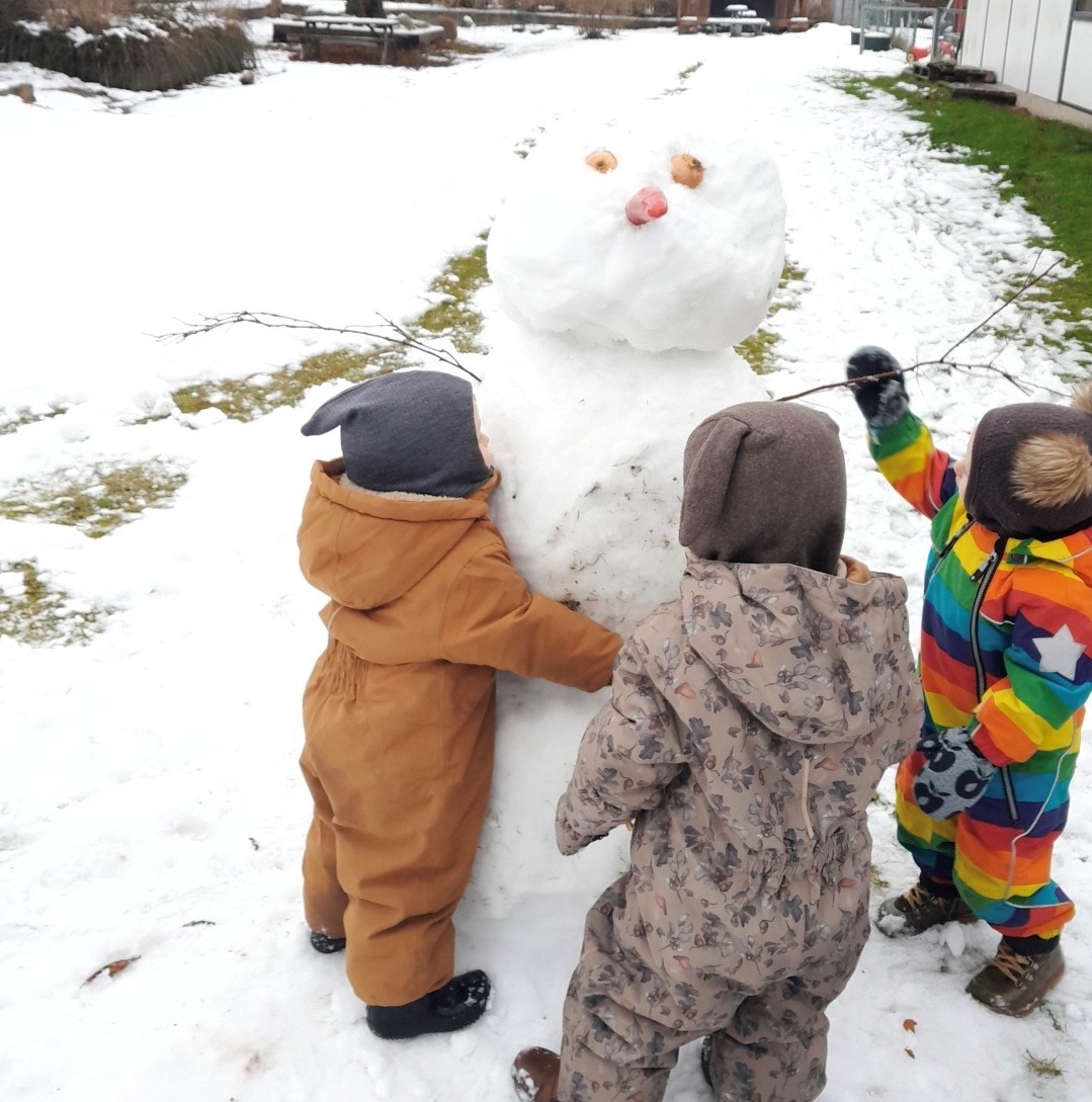 Børn i Tjærbyvejens Vuggestue leger med en snemand
